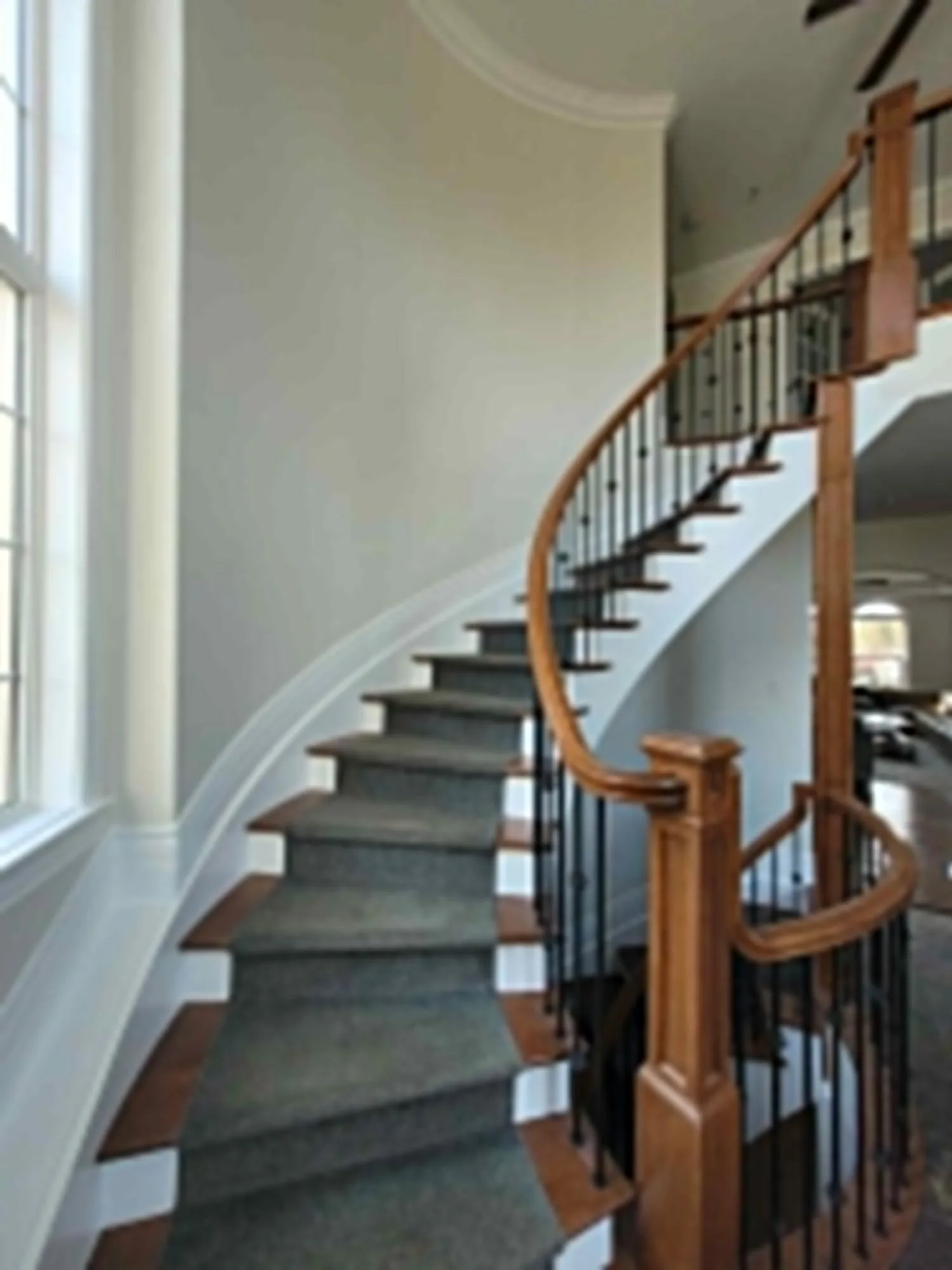 Custom curved hardwood staircase with black metal railings in Ottawa home